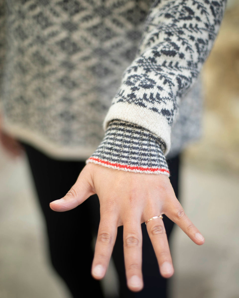 storm cuff stripey cuff detail on charcoal and pale grey fair isle sweater. a red highlight stripe on the cuff.