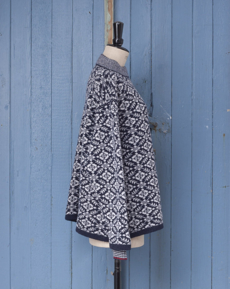 Modern Fair Isle sweater, made in Shetland. All over nordic pattern with striped inset cuff and stand up neck. Shown in navy and white with dark scarlet trim. Shown from the side.