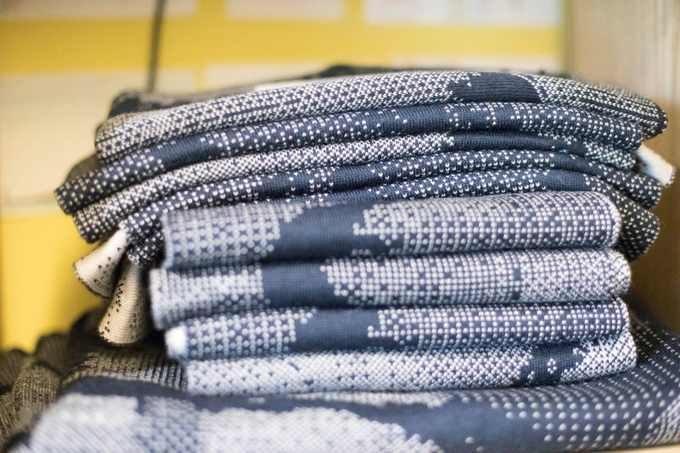 Knitted Rani scarf. Small abstract patterns make up a larger design with photographic imagery. Shown in inky blue and antique white