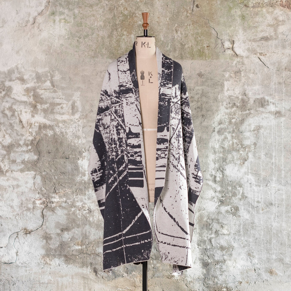Knitted Byre wrap/shawl. Abstract, graphic design in an asymmetric shape. Shown in Charcoal and stone white