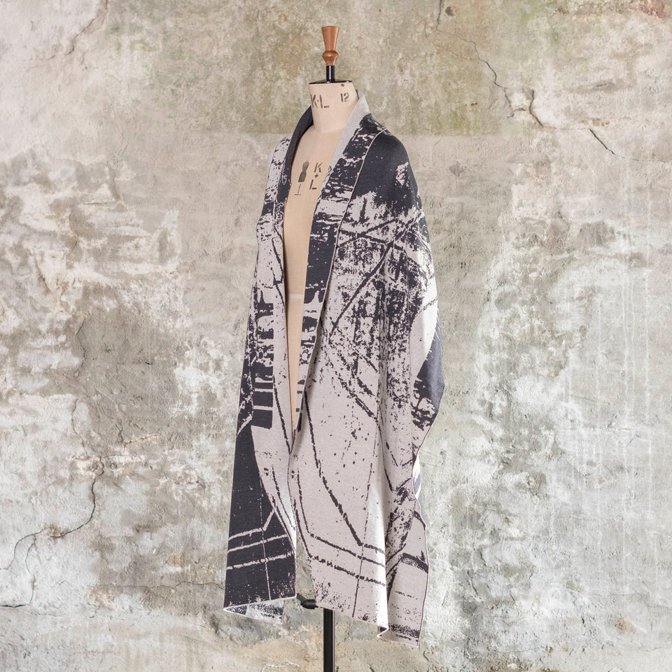 Knitted Byre wrap/shawl. Abstract, graphic design in an asymmetric shape. Shown in Charcoal and stone white