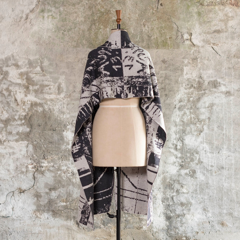 Knitted Byre wrap/shawl. Abstract, graphic design in an asymmetric shape. Shown in Charcoal and stone white