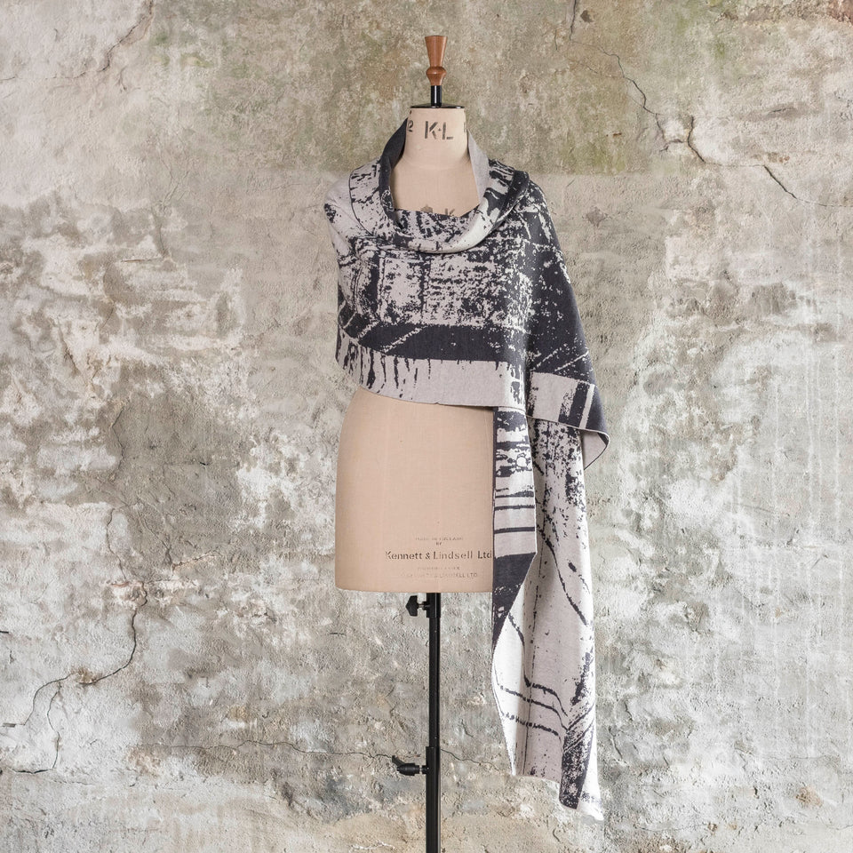 Knitted Byre wrap/shawl. Abstract, graphic design in an asymmetric shape. Shown in Charcoal and stone white
