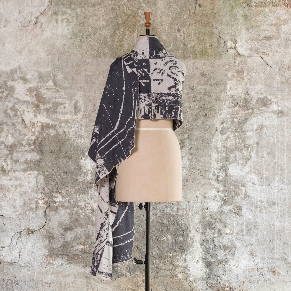Knitted Byre wrap/shawl. Abstract, graphic design in an asymmetric shape. Shown in Charcoal and stone white