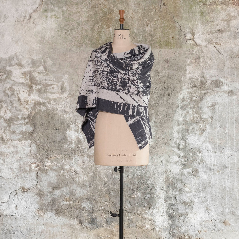 Knitted Byre wrap/shawl. Abstract, graphic design in an asymmetric shape. Shown in Charcoal and stone white