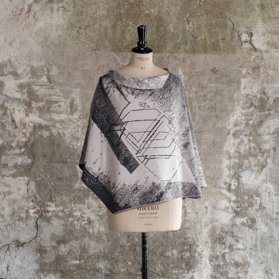 Knitted Byre cape. Abstract, graphic design in an asymmetric shape. Shown in Charcoal and stone white