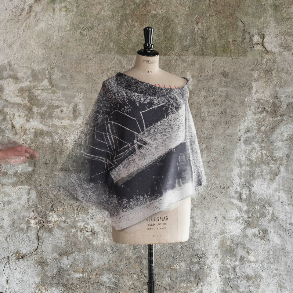 Knitted Byre cape. Abstract, graphic design in an asymmetric shape. Shown in Charcoal and stone white