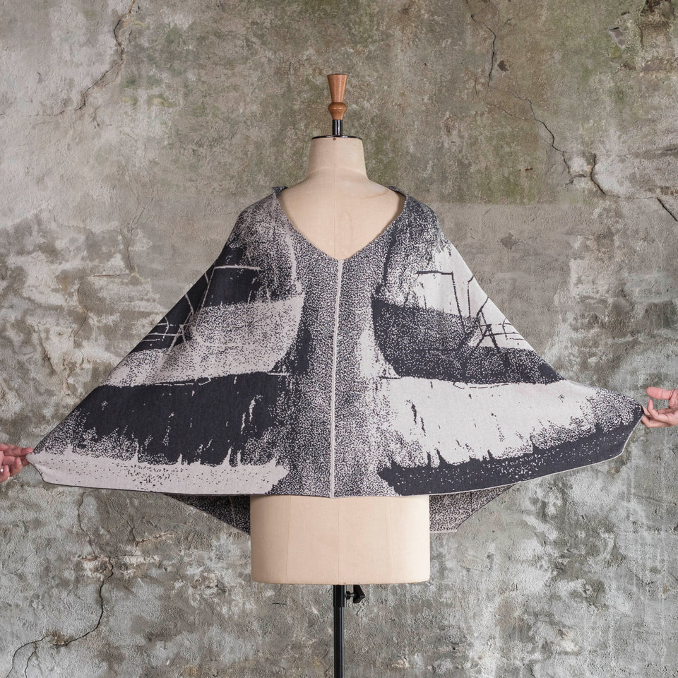 Knitted Byre cape. Abstract, graphic design in an asymmetric shape. Shown in Charcoal and stone white