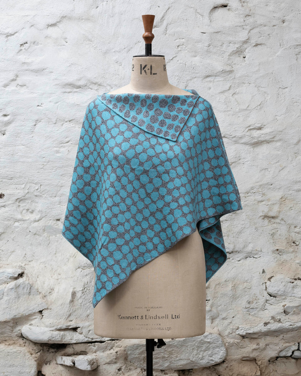 Knitted cape with an irregular dot design in two colours. Show in pale blue and marled grey