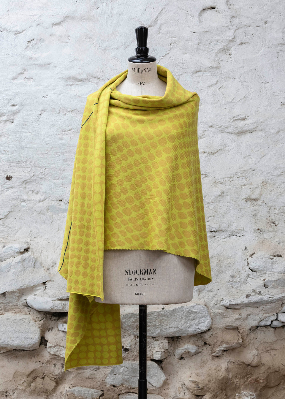 Knitted ebb-stanes wrap with irregular dot pattern shown in golds