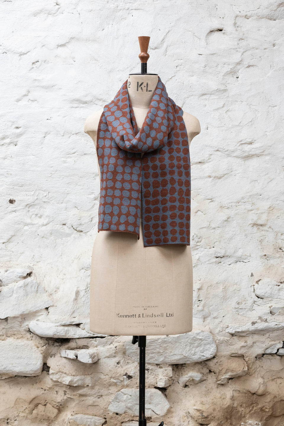 Knitted scarf with an irregular dot design in two colours. Show in dark rust and purples