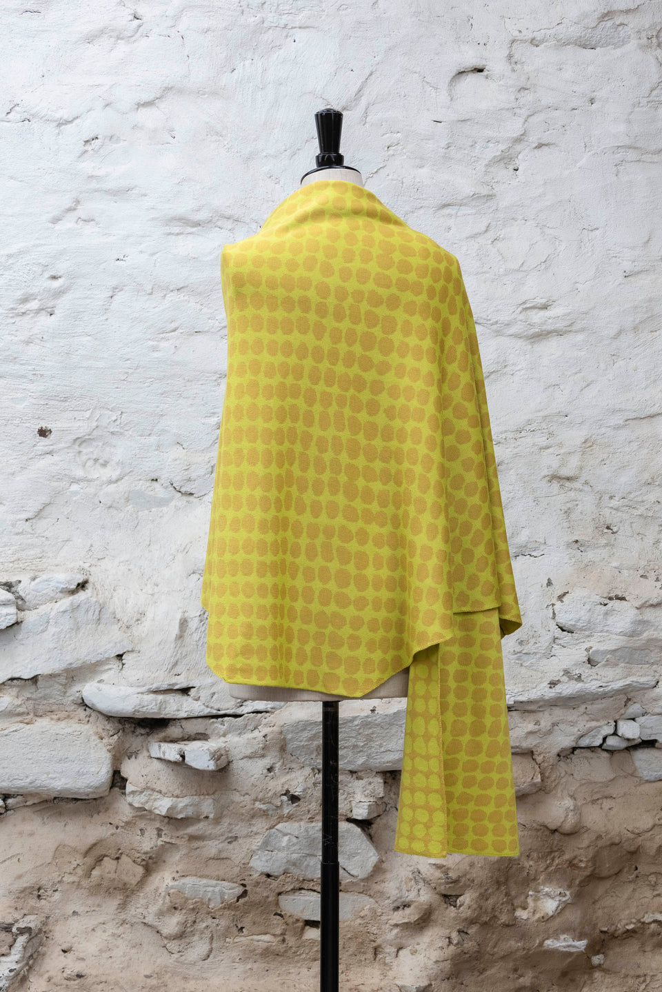 Knitted ebb-stanes wrap with irregular dot pattern shown in golds