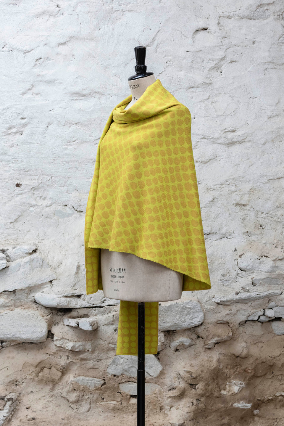 Knitted ebb-stanes wrap with irregular dot pattern shown in golds