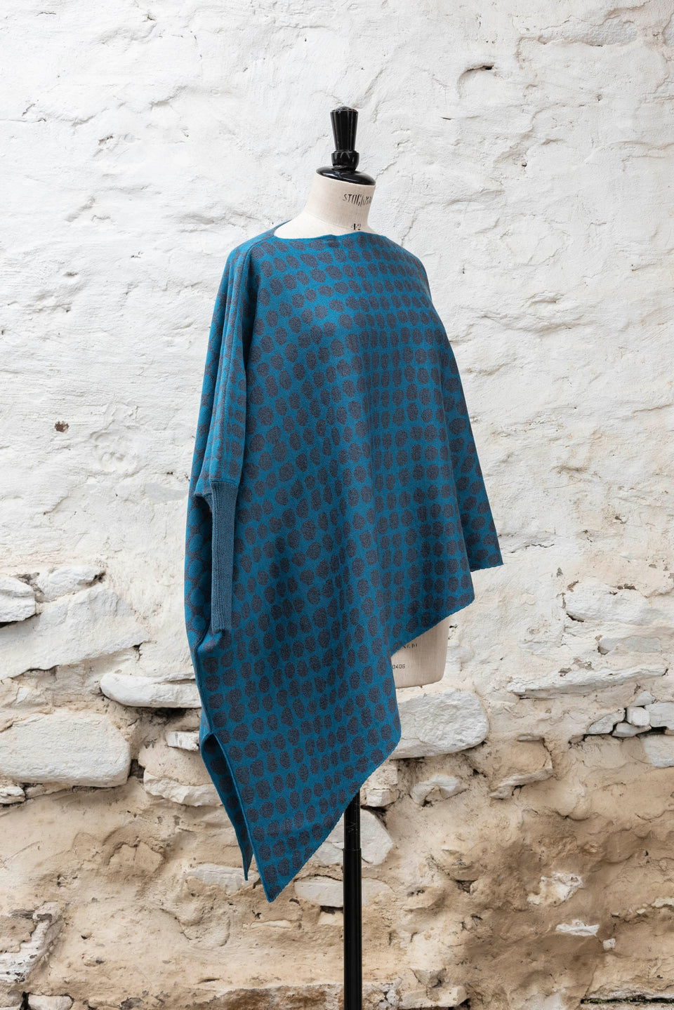 knitted asymmetric jumper with an irregular dot pattern. Shown in blues