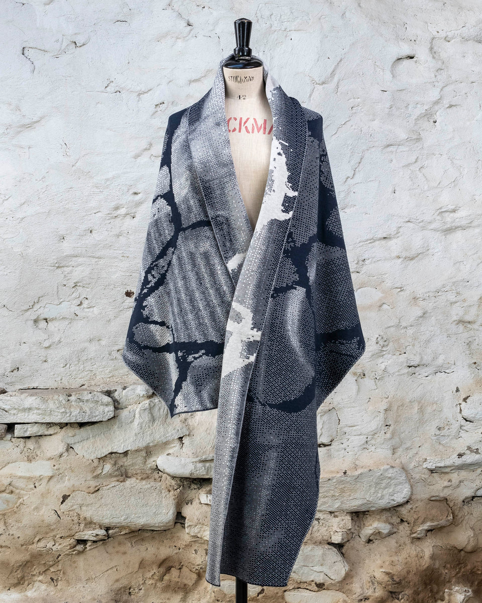 Knitted Rani shawl / wrap. Small abstract patterns make up a larger design with photographic imagery. Shown in inky blue and antique white