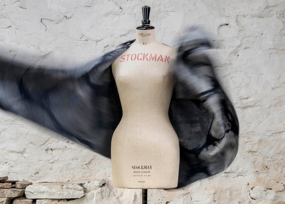 Knitted Rani shawl / wrap. Small abstract patterns make up a larger design with photographic imagery. Shown in inky blue and antique white