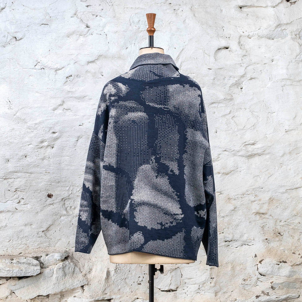 Knitted Rani jumper. Small abstract patterns make up a larger design with photographic imagery. Shown in inky blue and antique white