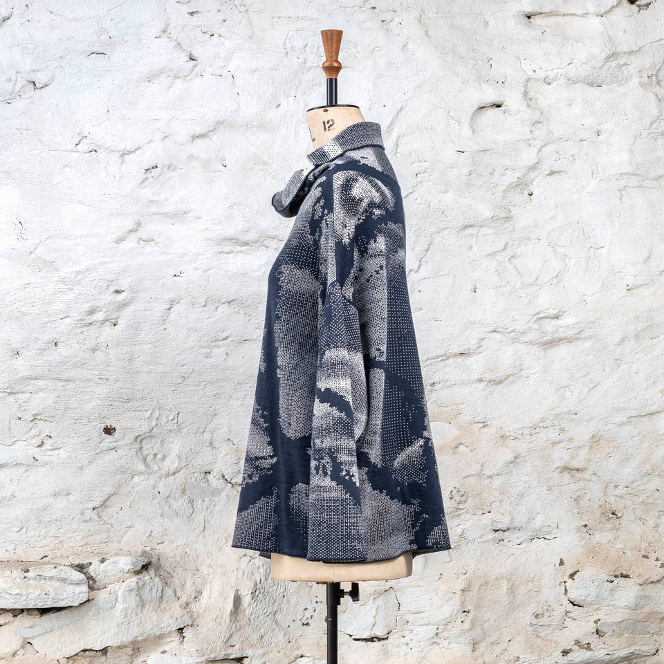 Knitted Rani jumper. Small abstract patterns make up a larger design with photographic imagery. Shown in inky blue and antique white