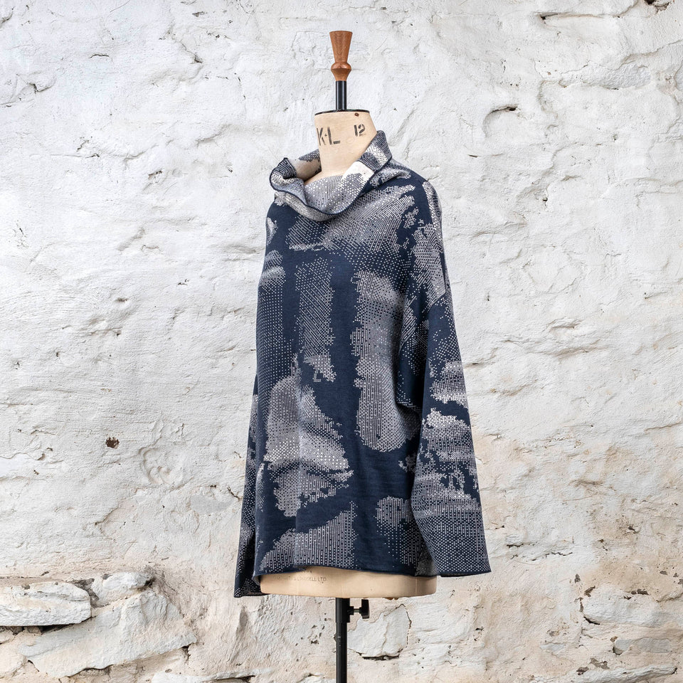 Knitted Rani jumper. Small abstract patterns make up a larger design with photographic imagery. Shown in inky blue and antique white