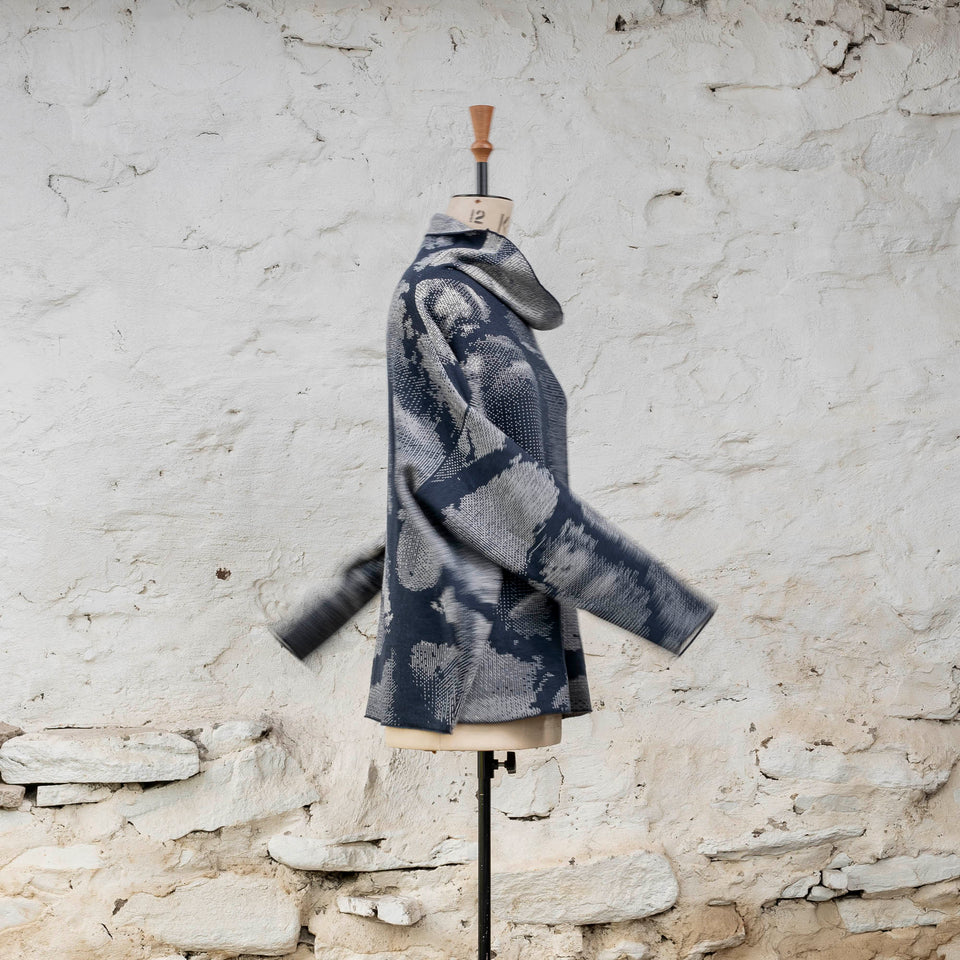 Knitted Rani jumper. Small abstract patterns make up a larger design with photographic imagery. Shown in inky blue and antique white