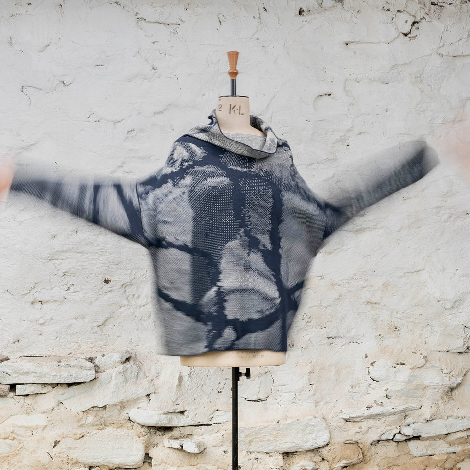 Knitted Rani jumper. Small abstract patterns make up a larger design with photographic imagery. Shown in inky blue and antique white