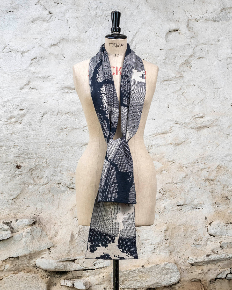 Knitted Rani scarf. Small abstract patterns make up a larger design with photographic imagery. Shown in inky blue and antique white