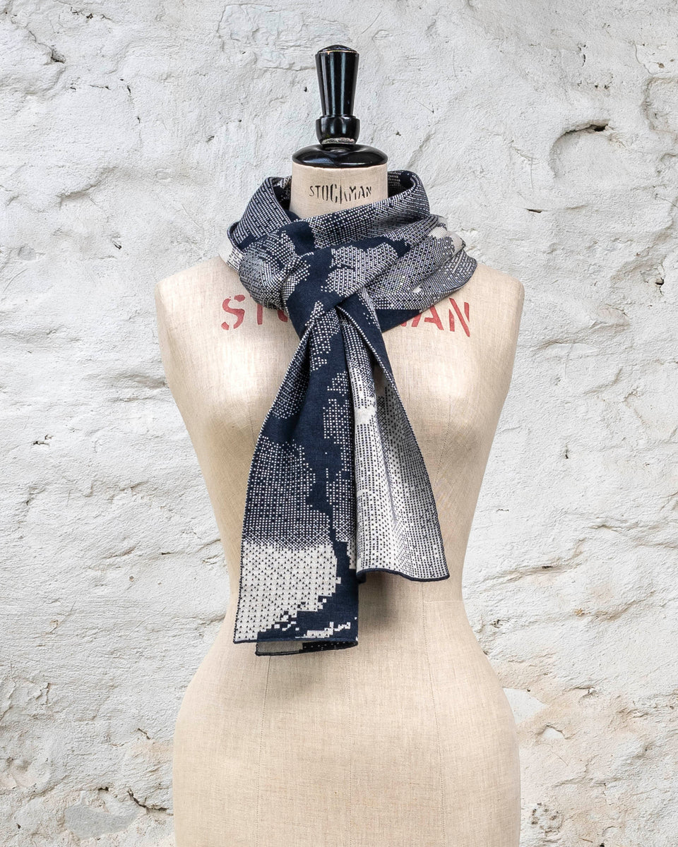 Knitted Rani scarf. Small abstract patterns make up a larger design with photographic imagery. Shown in inky blue and antique white