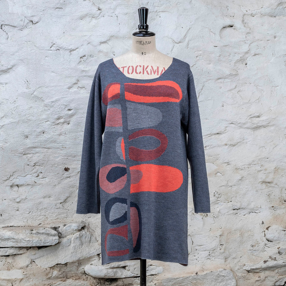 Knitted sleevletunic in blues with accents in coral. The pattern is abstract