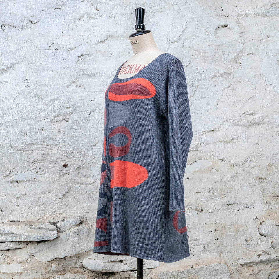 Knitted sleevletunic in blues with accents in coral. The pattern is abstract