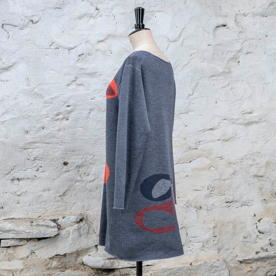 Knitted sleevletunic in blues with accents in coral. The pattern is abstract