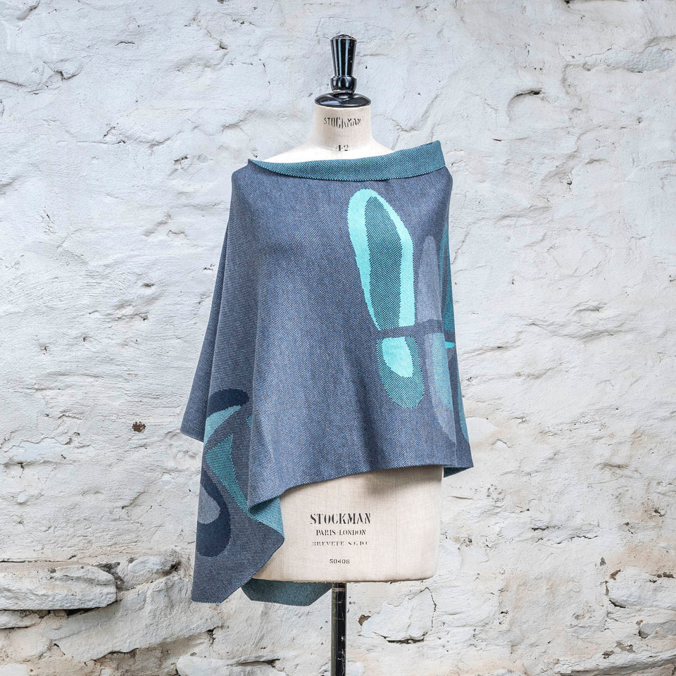 Knitted cape in blues with accents in aqua. The pattern is abstract
