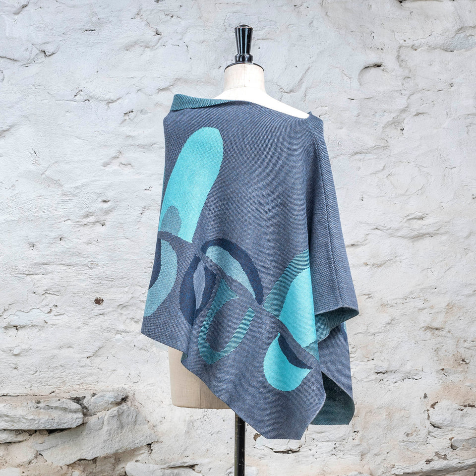 Knitted cape in blues with accents in aqua. The pattern is abstract