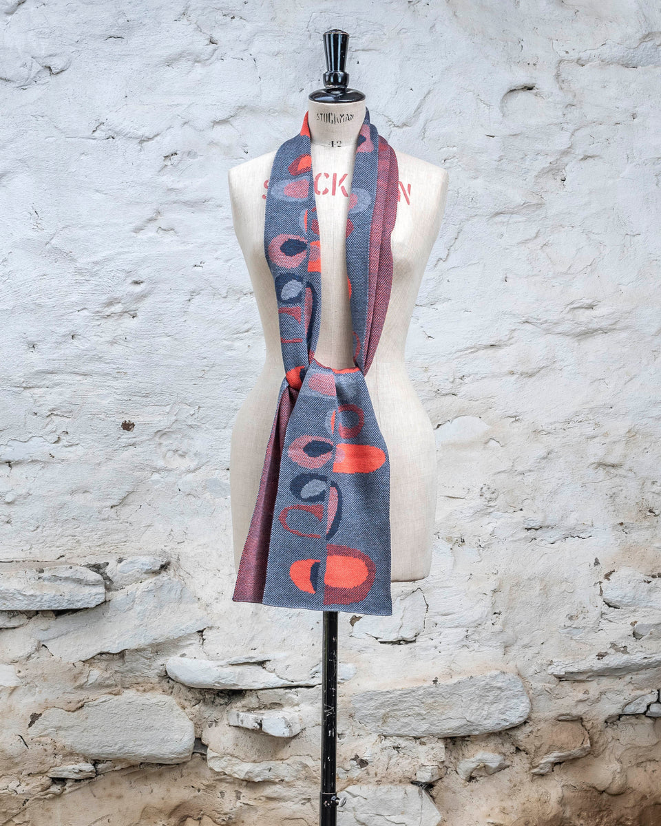 Knitted scarf in blues with accents in coral. The pattern is abstract