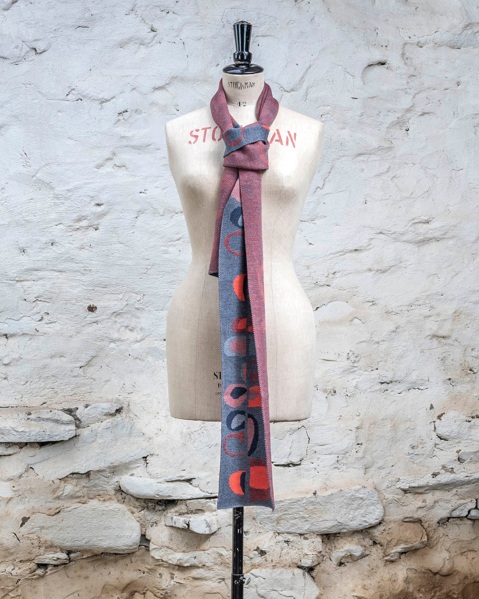 Knitted scarf in blues with accents in coral. The pattern is abstract