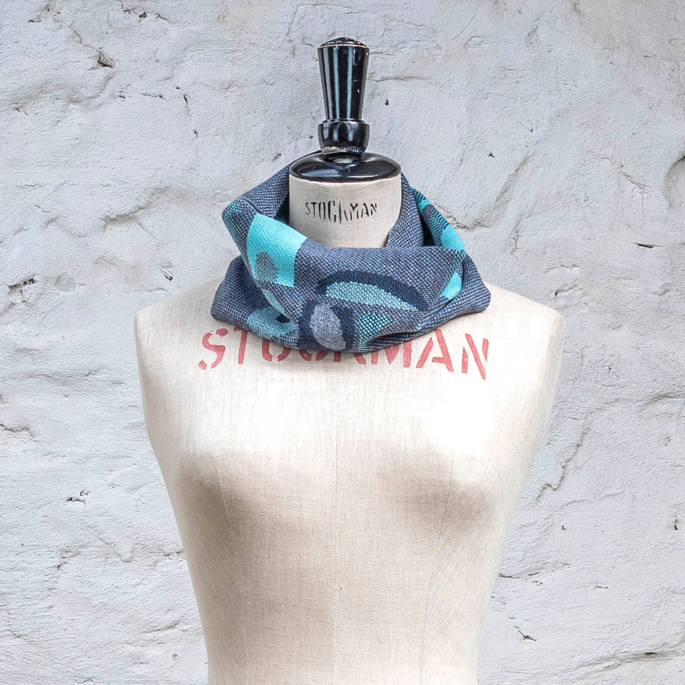 Knitted cowl in blues with accents in aqua. The pattern is abstract