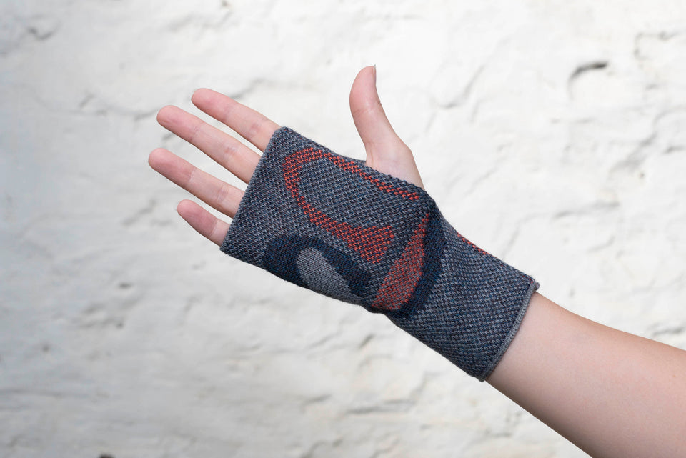 Knitted gauntlet mitts in blues with accents in coral. The pattern is abstract