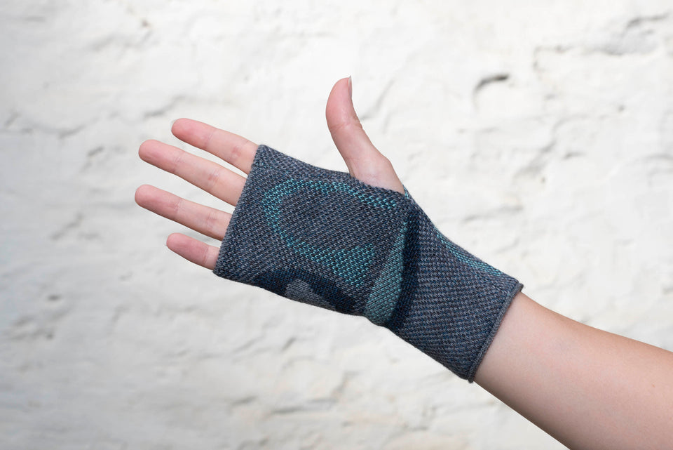 Knitted gauntlet mitts in blues with accents in aqua. The pattern is abstract