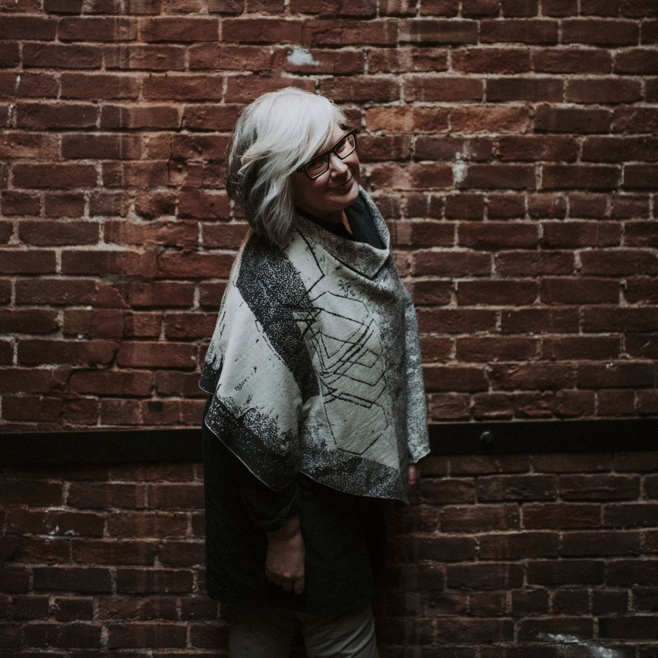 Knitted Byre cape. Abstract, graphic design in an asymmetric shape. Shown in Charcoal and stone white