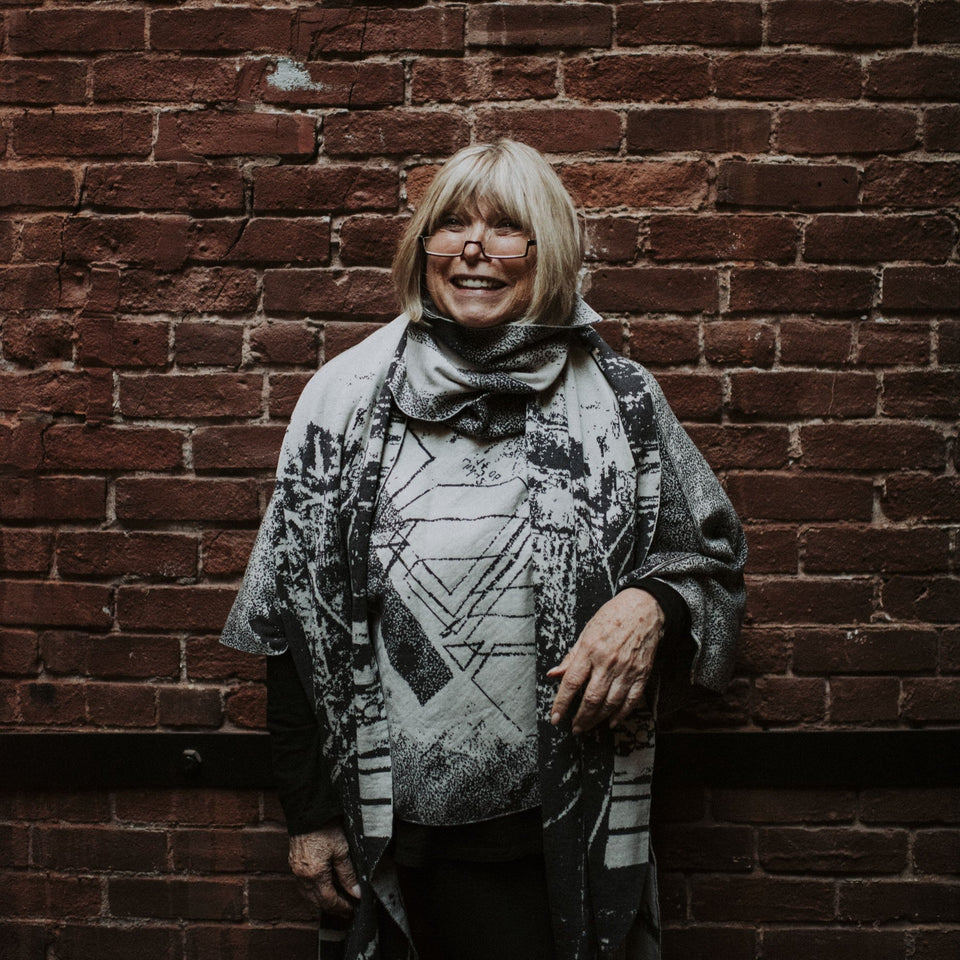 Knitted Byre cape. Abstract, graphic design in an asymmetric shape. Shown in Charcoal and stone white, with Byre wrap