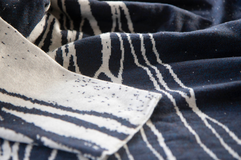 swatch of shoormal jumper showing the side with pattern in off-white on smoky blue and a sleeve in white with blue.. the blue yarn is actually a marl of mocha and blue.