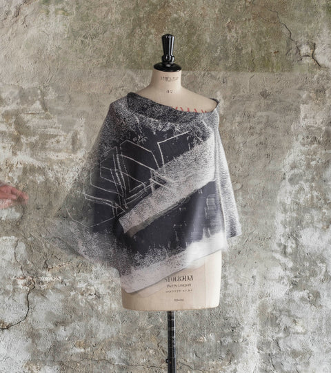 Contemporary knitted cape in an abstract design in charcoal and stone white fine merino yarn. Shown on a vintage mannequin, which is spinning - allowing the cape to fly out