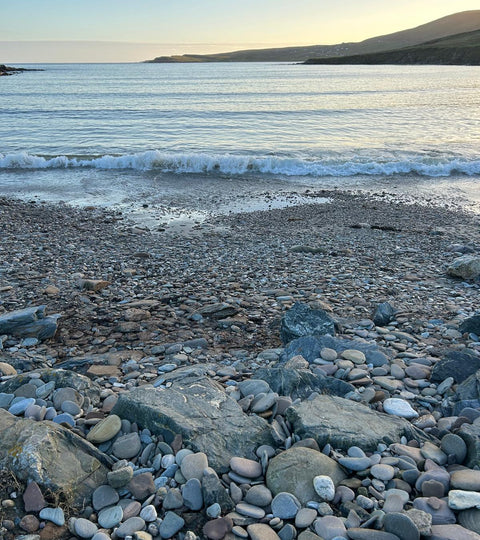 The pebbly beach at Hoswick, Shetland. On a clear autumn day in the late afternoon the light is beginning to go. In the distance the headland at Levenwick.