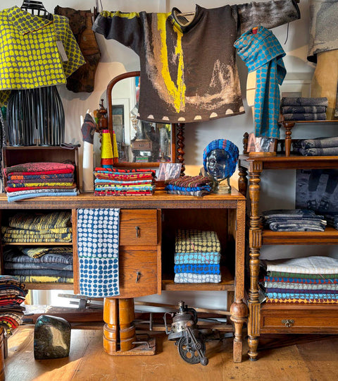 In the Nielanell Knitwear studio shop, Hoswick Shetland. Stacks of knitwear on vintage wooden furniture and arranged on mannequins. Fair Isle jumpers, contemporary abstract patterns, many different colours.