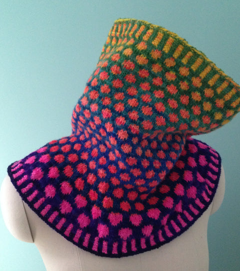 Knitted cowl on a mannequin. Spotted design in blues, pinks and greens, with ribbing on cuffs. Knitted in Fair Isle colourwork knitting.