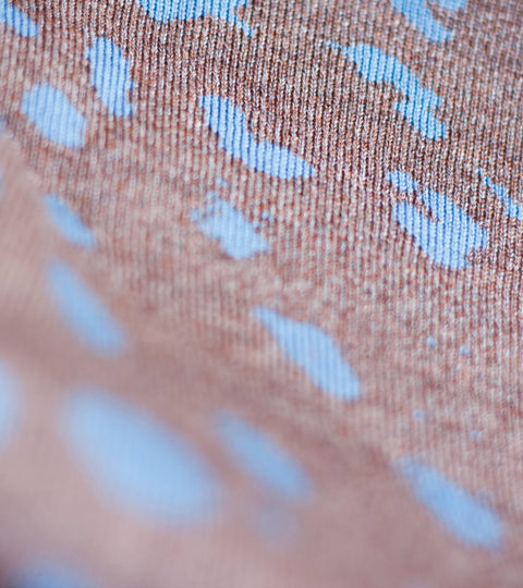 Close up view of a piece of Nielanell contemporary Shetland knitwear in the Marlet pattern. Mottled abstract pattern in bright blue and bronze merino