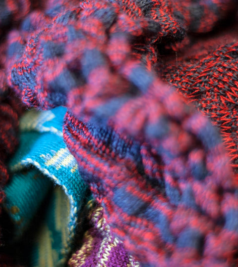 Contemporary British knitwear made in the Shetland Islands. Detail of jumper in blue and red striped, knitted fabric.