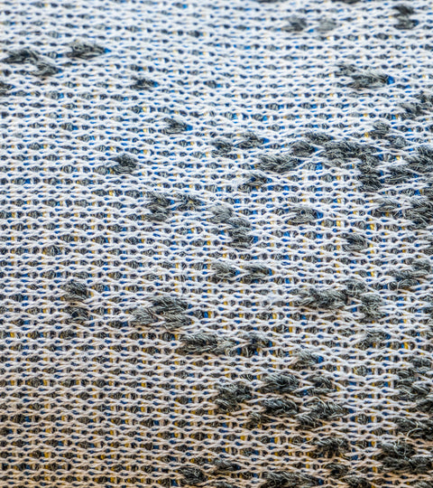 Close up of haar Shetland blanket, with different textured stitches in Shetland wool travelling over finer silk and merino. Greys