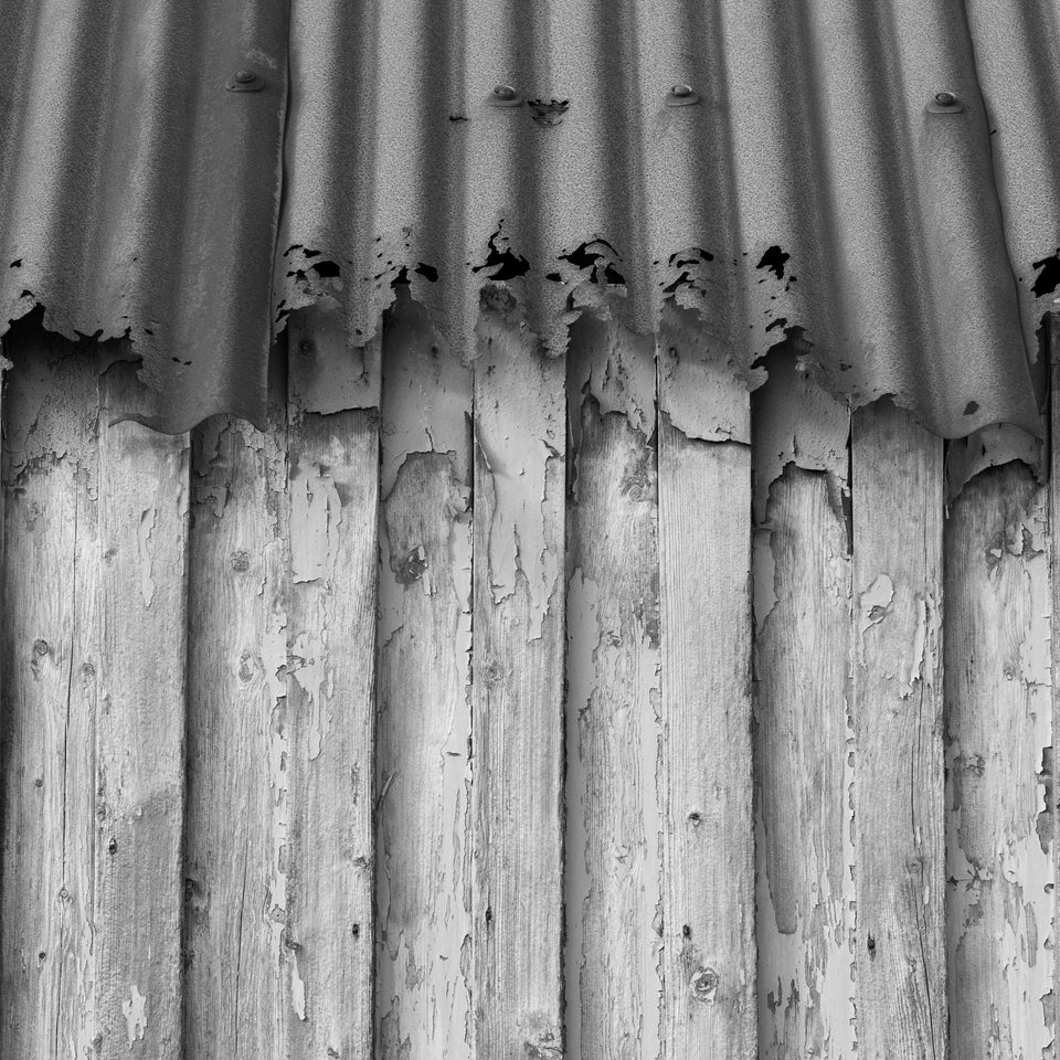 Detail of a wooden building with rusted crinkly tin roof