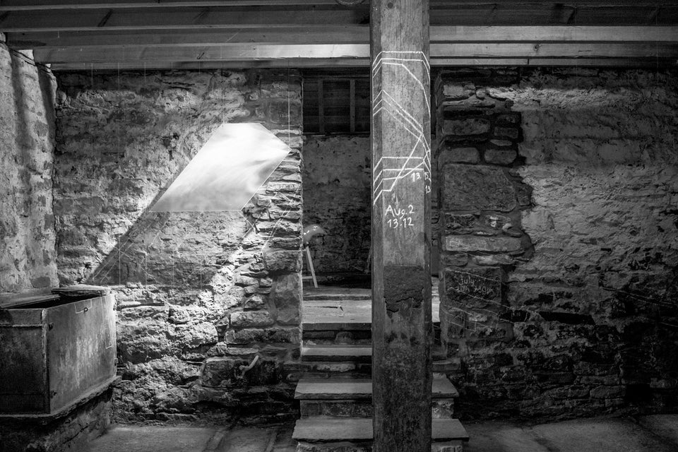 Black and white photograph inside the byre at Lathronwheel, Caithness. Installation of glass panels and chalk drawings on wooden pillar mapping light, by artist Karlyn Sutherland.