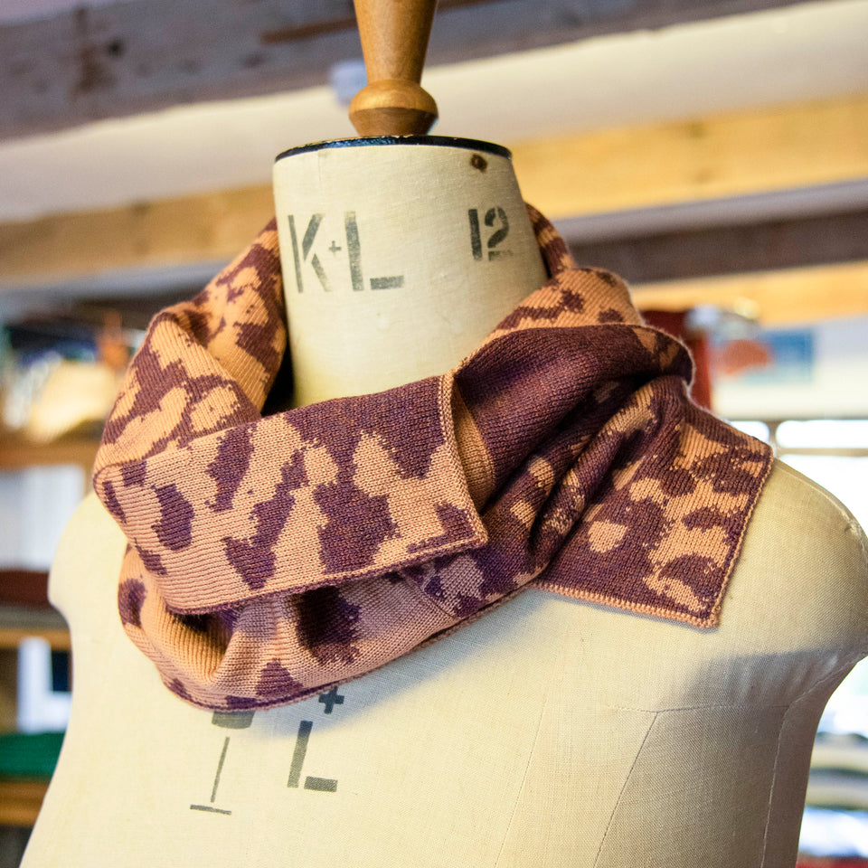 Asymmetric circle scarf in salmon and soft aubergine, in a mottled pattern on a mannequin in the Nielanell knitwear studio, Shetland.